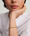 Woman's hand wearing a 14k solid gold Letter Bracelet, showcasing a delicate chain with an initial charm, perfect for wrist stacking.