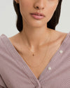 Woman wearing the Sia Birthstone Pendant Necklace, featuring a sparkling gemstone on a chain, perfect for personal or gift occasions.