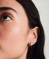 Close-up of a woman's ear showcasing Bold Huggie Hoops, formerly known as Bold Hoops, highlighting their sleek and stylish design.